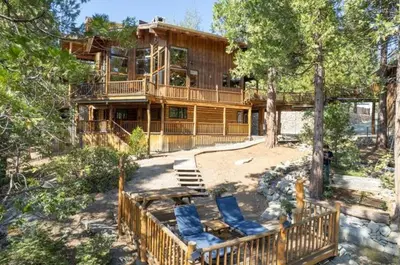 a large wooden house with a deck and chairs at Waterfall Lodge Yellowstone Vibes AC Space in Shaver Lake