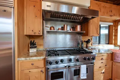 a kitchen with a stainless steel stove and wooden cabinets at Waterfall Lodge Yellowstone Vibes AC Space in Shaver Lake