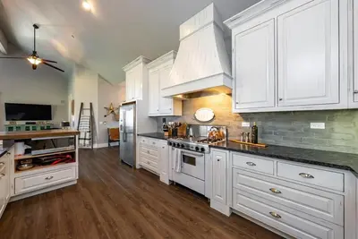 a large white kitchen with white cabinets and wooden floors at The Great Escape Sunsets Hot Tub Bliss in Shaver Lake
