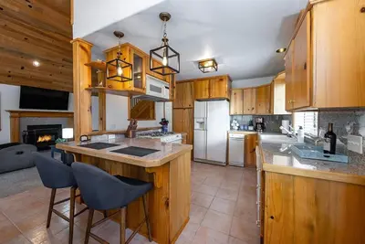 a kitchen with wooden cabinets and a kitchen island with chairs at The Knotty Sparrow Prime Spot Smores Nights in Shaver Lake