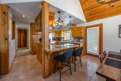 a kitchen with wooden cabinets and a island with bar stools at The Knotty Sparrow Prime Spot Smores Nights in Shaver Lake