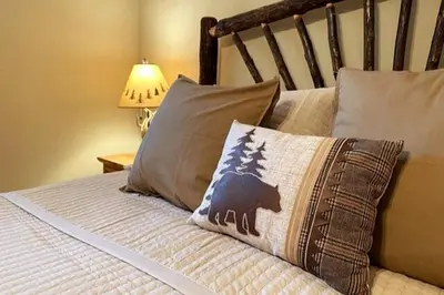 a bed with a pillow with a bear on it at Shady Pines Smores, Stars & Cozy Nights In in Shaver Lake