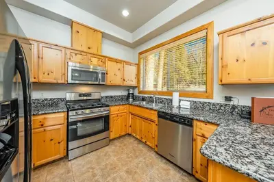 a kitchen with wooden cabinets and stainless steel appliances at Sierra Pines Villa Deck Jetted Tub Game Rm in Shaver Lake