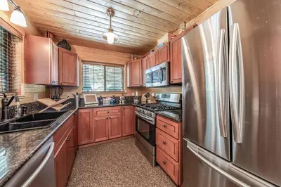 a kitchen with wooden cabinets and a stainless steel refrigerator at The Stew Cabin Cozy Escape Fireside Memories in Shaver Lake