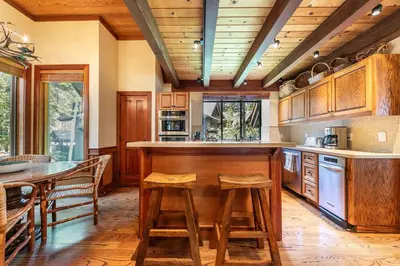 a kitchen with wooden cabinets and a table and chairs at Chambers Lakeside Escape w Lake Views & HOA Access! in Homewood