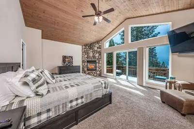a bedroom with a large bed and windows at Sunset Mountain Hot Tub, Fire Table, Epic Views in Shaver Lake