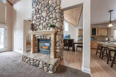 a fireplace in a living room with a stone wall at Sunset Mountain Hot Tub, Fire Table, Epic Views in Shaver Lake