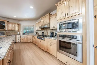 a kitchen with wooden cabinets and stainless steel appliances at Sunset Mountain Hot Tub, Fire Table, Epic Views in Shaver Lake