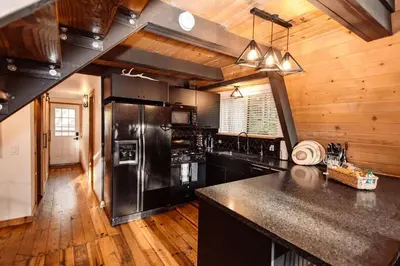 a kitchen with black appliances and a wooden ceiling at Modern Black A-Frame overlooking a Meadow w AC! in Shaver Lake