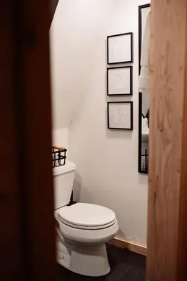 a bathroom with a toilet and three pictures on the wall at Modern Black A-Frame overlooking a Meadow w AC! in Shaver Lake
