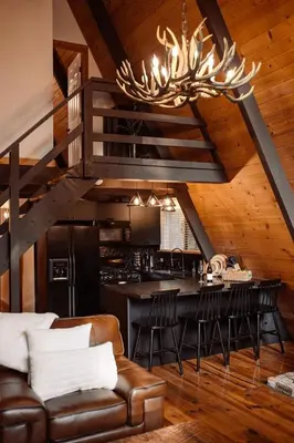 a kitchen and living room with a chandelier at Modern Black A-Frame overlooking a Meadow w AC! in Shaver Lake