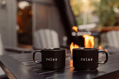 two black coffee cups sitting on a table with flames at Modern Black A-Frame overlooking a Meadow w AC! in Shaver Lake