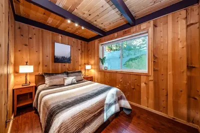 a bedroom with wooden walls and a bed with a window at A-Frame Escape Unique stay w comfort & style in Shaver Lake