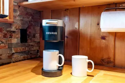 two coffee mugs sitting on the floor next to a coffee maker at A-Frame Escape Unique stay w comfort & style in Shaver Lake
