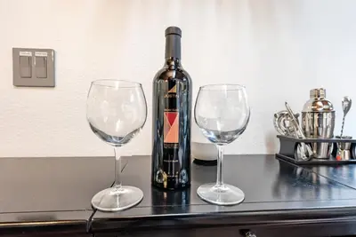a bottle of wine and two wine glasses on a counter at Creekside Cabin - Pup-Friendly with AC in Shaver Lake