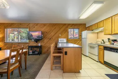 a kitchen with wooden walls and a table and a television at Spacious 1br Condo w/Partial Lake View #117 at Donner Lake Village in Truckee