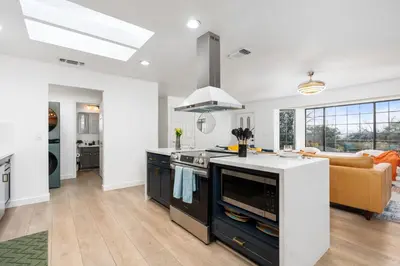 a kitchen with a stove top oven next to a living room at Secluded Mtn Top Family Haven with Spa, Views & Arcade in Oakhurst