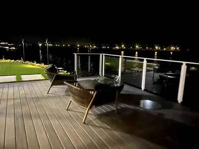a deck with a table and chairs on the water at night at Waterfront Resort Style Villa - 5 min to fastwater in Oakley