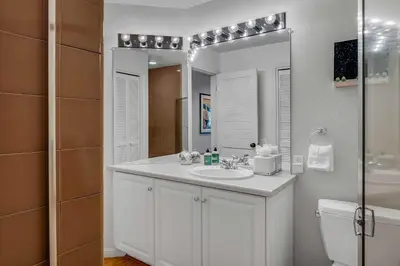 a white bathroom with a sink and a mirror at Palisades Condo - Walk to Ski Lift! in Olympic Valley
