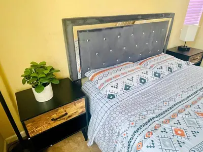 a bed with a blue comforter and a plant on a table at Cheerful & Spacious house to relax and unwind in Tracy