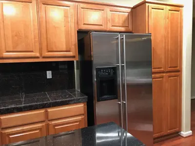 a kitchen with a stainless steel refrigerator and wooden cabinets at Cheerful & Spacious house to relax and unwind in Tracy
