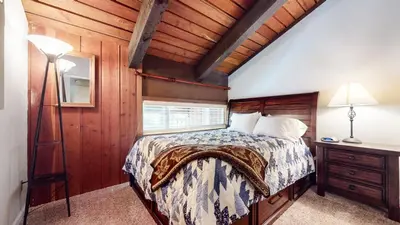 a bedroom with a bed and a wooden wall at Mammoth Ski & Racquet Club #118 condo in Mammoth Lakes