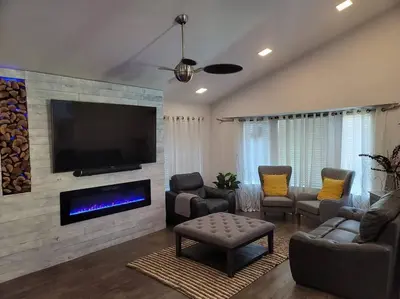 a living room with a tv on a brick wall at 3 Bedrooms,Beautiful House with Hot Tub, Pool Oasis and Fire Pit in Clovis