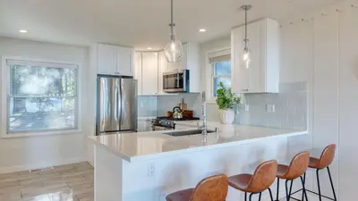 a kitchen with white cabinets and a stainless steel refrigerator at West Shore Lake House by AvantStay Ski Cabin w Backyard Sledding Hill in Homewood