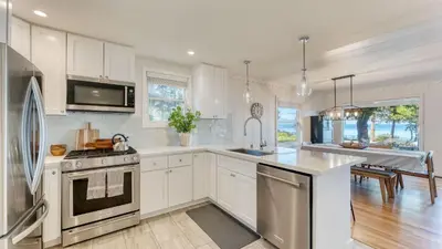 a kitchen with white cabinets and stainless steel appliances at West Shore Lake House by AvantStay Ski Cabin w Backyard Sledding Hill in Homewood