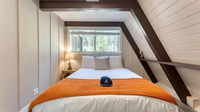 a bedroom with a bed with an orange blanket and a window at Speckled by AvantStay Modern Interior 0.5mi to Lake in Kings Beach