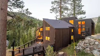 a cabin in the woods with a deck and trees at Trapper by AvantStay A Interior Design w Sauna in Alpine Meadows