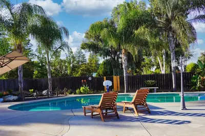two chairs and an umbrella next to a swimming pool at Fernwood Retreat at Madera Ranchos in Madera