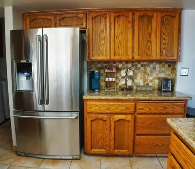 a kitchen with a stainless steel refrigerator and wooden cabinets at Fernwood Retreat at Madera Ranchos in Madera