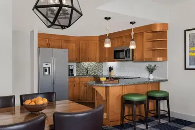 a kitchen with wooden cabinets and a table with green stools at Marriott Grand Residences Luxury 1BD in South Lake Tahoe