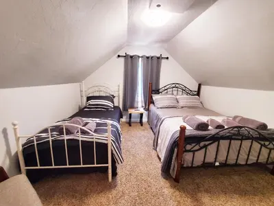 a attic room with two beds and a window at -Serendipity Lodge at Yosemite- BBQ-Full Kitchen-King Bed in Oakhurst