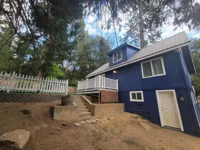 a blue tiny house in a yard with a fence at -Serendipity Lodge at Yosemite- BBQ-Full Kitchen-King Bed in Oakhurst