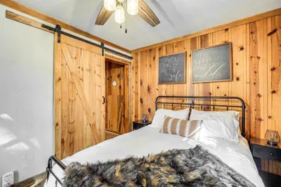 a bedroom with a bed with wooden walls and a chalkboard at Hike, Ski and Fish Charming Cabin in Twain Harte! in Twain Harte