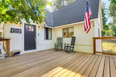 a house with a deck with two chairs and an american flag at Hike, Ski and Fish Charming Cabin in Twain Harte! in Twain Harte