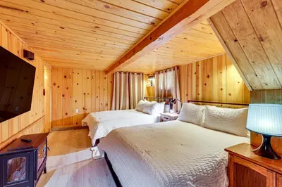 a bedroom with two beds in a room with wooden walls at Peaceful Wooden Cabin, 2 Mi to Bass Lake! in Oakhurst
