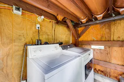a washer and dryer in a room with wooden walls at Peaceful Wooden Cabin, 2 Mi to Bass Lake! in Oakhurst
