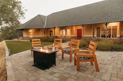 a patio with a table and chairs and a building at Panoramic Lookout Sierra Serenity BBQ by CasaOso in Mariposa