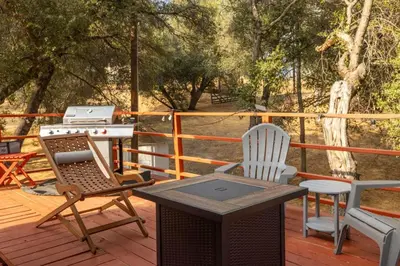a grill and two chairs on a deck with a table at HIlltop Oasis with games, hot tub, Fire-pit, Deck, Views in Oakhurst