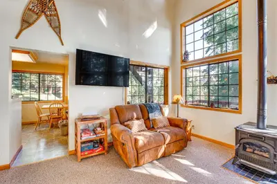 a living room with a leather couch and a stove at Deck with Mountain Views Cabin in Bear Valley! in Bear Valley
