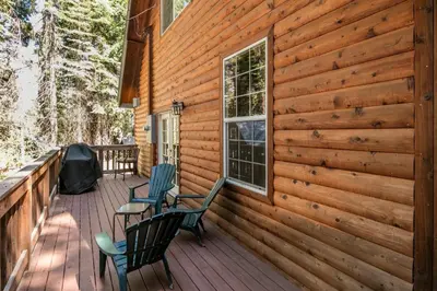 a deck with two chairs and a window at Cabin minutes from Yosemite in Fish Camp