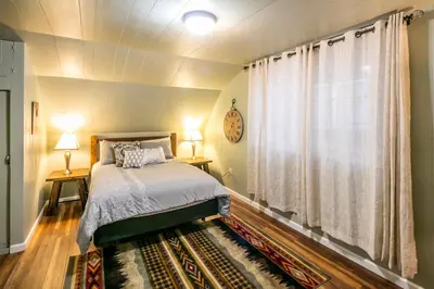 a bedroom with a bed and two lamps and a window at Cabin minutes from Yosemite in Fish Camp