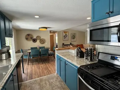 a kitchen with blue cabinets and a living room at Manzanita Hideaway Hot Tub Sunset views Yosemite in Ahwahnee