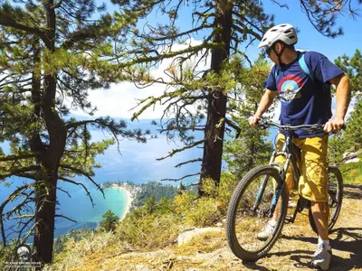 a man riding a bike on a trail near trees at Luxe 4 lake Tahoe Luxury With Hot Tub in Stateline