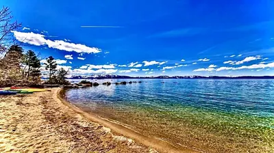a beach with water and trees and a blue sky at Lv12 luxury villa with hot tub, close to skiing in Glenbrook