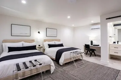 a white bedroom with two beds and a desk at Hotel Bayit in Modesto