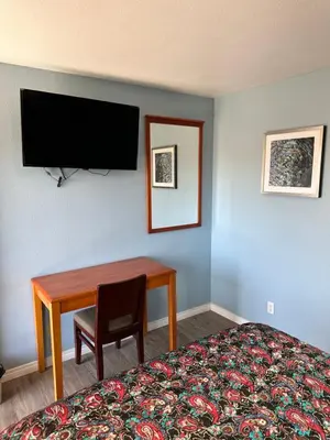 a room with a bed and a desk and a television at Corcoran Inn in Corcoran